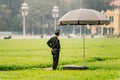 Vietnamese police officers standing under umbrella on the green field in front of Ho Chi Minh Mausoleum at Hanoi, Vietnam