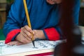 Vietnamese scholar writes calligraphy at lunar new year. Calligraphy festival is a popular tradition during Tet holiday. Text in p