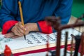 Vietnamese scholar writes calligraphy at lunar new year. Calligraphy festival is a popular tradition during Tet holiday. Text in p