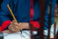 Vietnamese scholar writes calligraphy at lunar new year. Calligraphy festival is a popular tradition during Tet holiday. Text in p