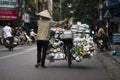 A vietnamese seller pushing her bike full of porcelain goods for sale in a street of Hanoi, Vietnam. Street Vendor on bicycle