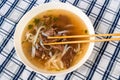 Vietnamese spicy soup Pho Bo with beef, noodle and herb in plate, chopstick