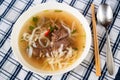 Vietnamese spicy soup Pho Bo with beef piece, noodle and herb, chopstick and spoon