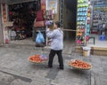 Vietnamese street vendor in Hanoi, with bamboo frame over shoulder carrying two big baskets of tomatoes for sale