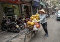 Vietnamese street vendor in Hanoi, on bicycle carrying goods for sale.