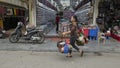 Vietnamese street vendor in Hanoi, walking along a street carrying two baskets of food held by a bamboo frame over her shoulder Royalty Free Stock Photo