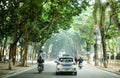 Vietnamese travel along a tree-lined street in the middle of Hanoi, Vietnam