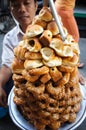 Vietnamese vendor selling small donuts piled high on a tray on the street
