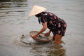 A vietnamese woman catches shells