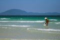 A Vietnamese woman is collecting sea shells on the shore in Nha Trang, Vietnam Royalty Free Stock Photo