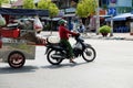 Vietnamese woman ride motorbike pull food cart stop on street