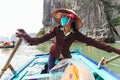 Vietnamese woman rowing boats that bring tourists traveling inside limestone cave with limestone island in background in summer.