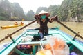 Vietnamese woman rowing boats that bring tourists traveling inside limestone cave with limestone island in background in summer. Royalty Free Stock Photo