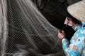 Vietnamese woman sewing fishing net