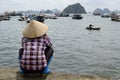 Vietnamese woman in traditional asina hat watching to Halong Bay