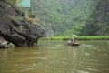 Vietnamese woman in traditional conical hat rows boat into natural cave on Ngo river, Tam Coc, Ninh Binh, Vietnam Royalty Free Stock Photo