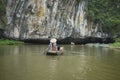 Vietnamese woman in traditional conical hat rows boat into natural cave on Ngo river, Tam Coc, Ninh Binh, Vietnam Royalty Free Stock Photo