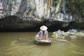 Vietnamese woman in traditional conical hat rows boat into natural cave on Ngo river, Tam Coc, Ninh Binh, Vietnam Royalty Free Stock Photo