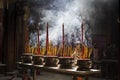 Vietnamese woman in traditional dress ao dai praying with incense stick in the burning pot of the Chinese pagoda in Ho Chi Minh