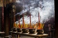 Vietnamese woman in traditional dress ao dai praying with incense stick in the burning pot of the Chinese pagoda in Ho Chi Minh Royalty Free Stock Photo