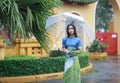 Vietnamese women wear Ao dai holding umbrella in the rain