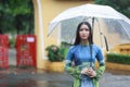 Vietnamese women wear Ao dai holding umbrella in the rain