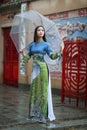 Vietnamese women wear Ao dai holding umbrella in the rain