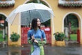 Vietnamese women wear Ao dai holding umbrella in the rain