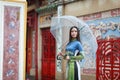 Vietnamese women wear Ao dai holding umbrella in the rain