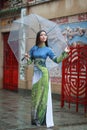 Vietnamese women wear Ao dai holding umbrella in the rain