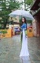 Vietnamese women wear Ao dai holding umbrella in the rain