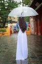 Vietnamese women wear Ao dai holding umbrella in the rain