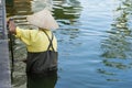 Vietnamese worker cleaning rubbish on lake. Manual work Royalty Free Stock Photo