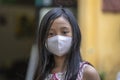 Vietnamese young girl with protective mask on the face on a street of the old city in Hoi An, Vietnam, close up