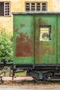 View of a abandoned and older rustic train wagon, yellow building as background