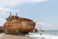 View of a abandoned ships carcasses in the ships cemetery, children bathing on the beach