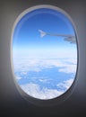 view from above from airliner oval window with wing portion in sight Royalty Free Stock Photo