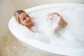 View from above on attractive young woman relaxing in bathtub and smiling to camera. Royalty Free Stock Photo