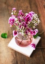View from above of beautiful bouquet of pink, white wax flower and purple cyclamen flowers in a glass vase.