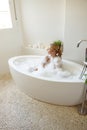 View from above on beautiful young cheerful female sitting in bathtub with bubbles foam. Royalty Free Stock Photo