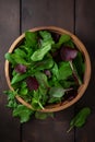 View from above of a bowl of green salad with spinach on dark wooden table. Image is AI generated.