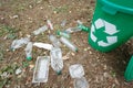 Green recycling bin next to plastic trash on a ground background. Containers for rubbish recycling. Environment, ecology Royalty Free Stock Photo