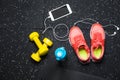 A top view of pink trainers, bottle for water, phone and small dumbells on a black background. Sports accessories. Royalty Free Stock Photo