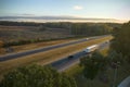 View from above of busy american highway with fast moving traffic between autumn woods. Interstate transportation