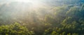 View from above of dark moody pine trees in spruce foggy forest with bright sunrise rays shining through branches in summer mounta Royalty Free Stock Photo