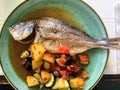 A view from above of a Delicious pan fried Mediterranean fish served on a plate with fresh vegetables at a restaurant