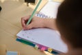 View from above with details on hand of a schoolchild, first grader learning the writing, writes letters in a copybook Royalty Free Stock Photo