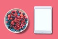 View from above. Different berries in a plate. Near the tablet with an assorted white screen. Royalty Free Stock Photo