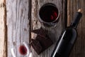 View from above of elegant bottle and wineglasses of red wine with dark chocolate on rustic wooden background. Wine and dessert.