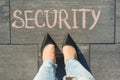 View from above, female feet with text security written on grey sidewalk.